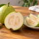 เตรียมฝรั่งเป็นของว่างให้สะดวก: จากผลสดสู่กล่องพร้อมกินอย่างพอดี 3 ผลฝรั่งทั้งผลและฝรั่งผ่าครึ่งข้างจานชิ้นฝรั่งบนโต๊ะไม้