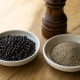 เครื่องเทศทั้งเมล็ดหรือแบบบด: จับรูปแบบให้เข้ากับเวลาปรุงและเนื้อสัมผัส 4 ถ้วยพริกไทยดำทั้งเมล็ดข้างถ้วยพริกไทยบดและเครื่องบดบนโต๊ะไม้